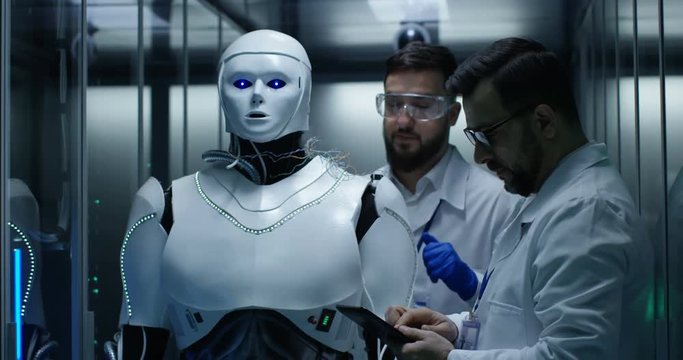 Medium shot of engineers testing on robot controls inside the laboratory