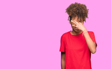 Beautiful young african american woman over isolated background smelling something stinky and disgusting, intolerable smell, holding breath with fingers on nose. Bad smells concept.