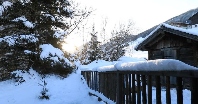 sunrise over snow covered hut and frence in winter