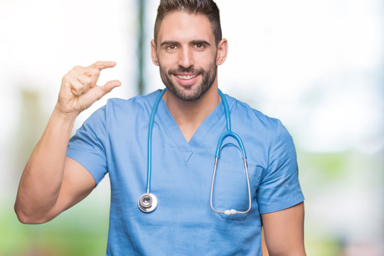 Handsome young doctor surgeon man over isolated background smiling and confident gesturing with hand doing size sign with fingers while looking and the camera. Measure concept.