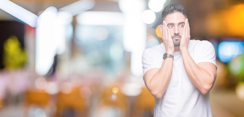Fototapeta na wymiar Handsome man wearing white t-shirt over night outdoors background Tired hands covering face, depression and sadness, upset and irritated for problem