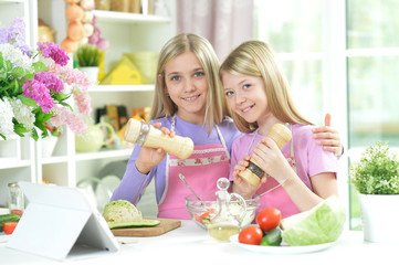 Two girls in pink aprons preparing fresh salad