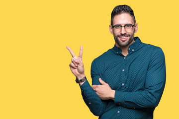 Young handsome business man wearing glasses over isolated background smiling with happy face winking at the camera doing victory sign. Number two.