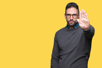 Young handsome man wearing glasses over isolated background doing stop sing with palm of the hand. Warning expression with negative and serious gesture on the face.