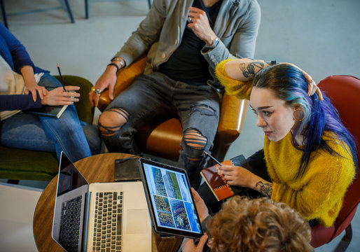 Colleagues and clients talking strategy with laptop and tablet.Top view.Group of multiethnic people having business team meeting in restaurant lounge.Teamwork,corporate,diversity and social concepts.