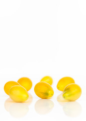 Seven Yellow Plum Tomatoes with White Background. Vertical White Copy Space Above Group of Organic Fruit (Tomatoes) from Local Farmers Market