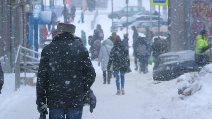 People walking on winter city street during snowstorm. Slow motion. Perm, Russia.