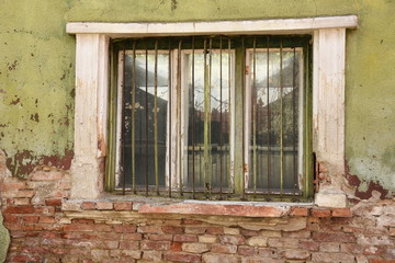 window with bars on a house in ruins  near  a bench in Bistrita,Romania