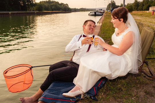 Brautpaar gl&uuml;cklich am Wasser am Hochzeitstag, gemeinsames Hobby Angeln beim Bier