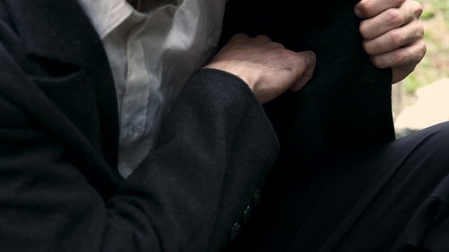 Closeup of a man pulling out a piece of paper from his coat pocket.