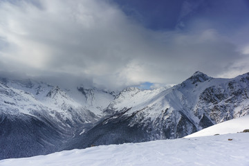 Fototapeta na wymiar Snow cloud covered the top of the main Caucasian ridge near the resort ski village Dombay