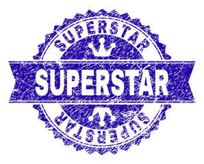 SUPERSTAR rosette stamp watermark with grunge style. Designed with round rosette, ribbon and small crowns. Blue vector rubber print of SUPERSTAR tag with grunge style.