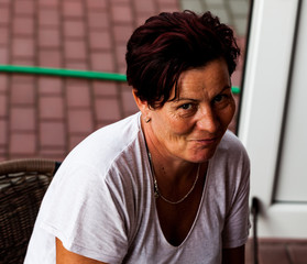 A woman looking straight with a mocking face. The hardworking mother resting on a rattan chair. Doing household errands. Typical activity of a housewife