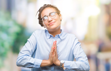 Young braided hair african american business girl wearing glasses over isolated background begging...