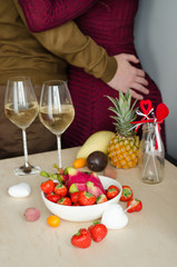 A couple drinking champagne with lying strawberries and exotic fruits. Valentine's Day. Romantic evening