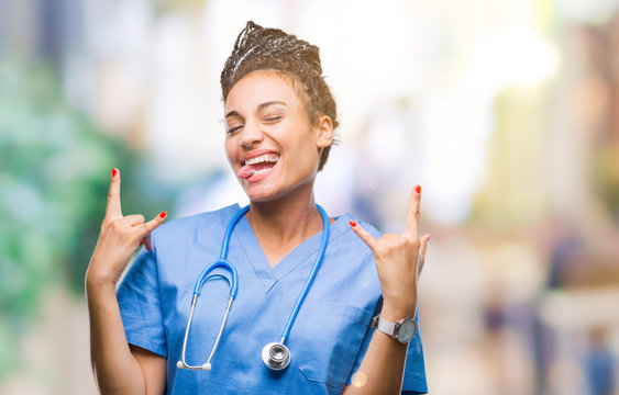 Young braided hair african american girl professional surgeon over isolated background shouting with crazy expression doing rock symbol with hands up. Music star. Heavy concept.
