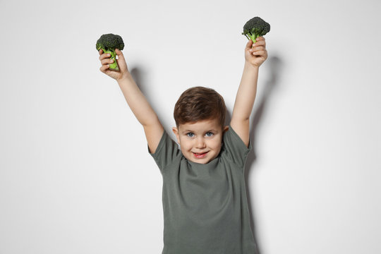 Adorable little boy with broccoli on white background