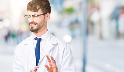Young professional scientist man wearing white coat over isolated background disgusted expression, displeased and fearful doing disgust face because aversion reaction. With hands raised