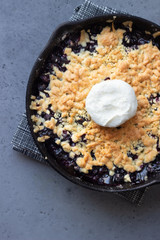 Obraz na płótnie Canvas Black currant crumble with vanilla ice cream in cast iron pan. Healthy food concept. Grey stone background. Top view. Copy space.