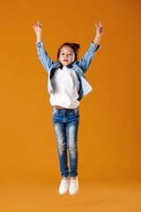 happy little child girl in jeans clothes jumping