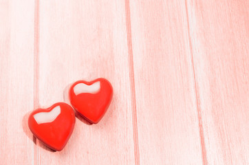Couple of glossy red hearts for Valentine's day on living coral colored wooden table