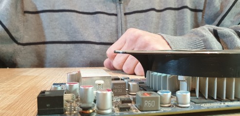 A man holds the item from the computer. Computer detail. Video card for the computer.