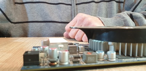 A man holds the item from the computer. Computer detail. Video card for the computer.
