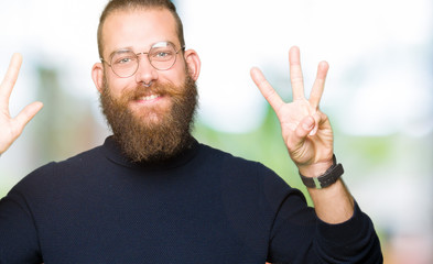 Naklejka premium Young blond man wearing glasses and turtleneck sweater showing and pointing up with fingers number eight while smiling confident and happy.