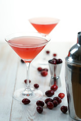 Cosmopolitan cocktail with cranberries, shaker and jigger. White wooden background, high resolution