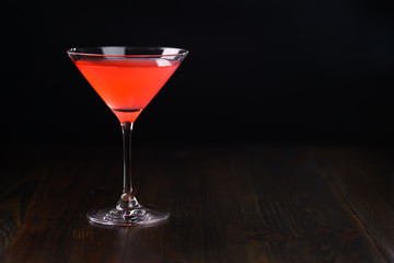 Cosmopolitan cocktail on a dark wooden background. High resolution, negative space