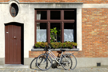 Fototapeta na wymiar bike near the wall of a brick house, next to the window and the door