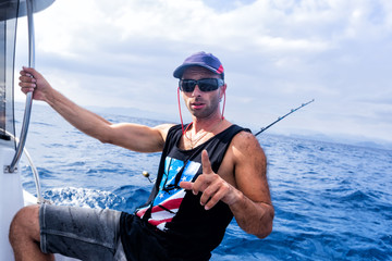 The brutal young man on sea fishing. Trolling.