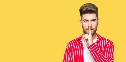 Young handsome man wearing red shirt asking to be quiet with finger on lips. Silence and secret concept.