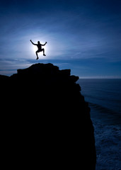 Jump for joy, in the air, above a cliff or mountain, blue sky, sunset, sunrise