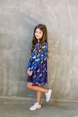 Naklejka premium Funny little girl wearing nice blue dress. Isolated on grey