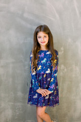 Funny little girl wearing nice blue dress. Isolated on grey
