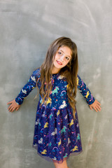Small girl child model in beautiful dress. Childhood, look, happiness, hairstyle. Kid fashion, hairdresser, birthday. Little girl with long hair on grey background.