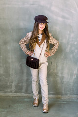 Beautiful little girl. Portrait. Studio shot of little girl in a light suit, a golden sneakers and a hat