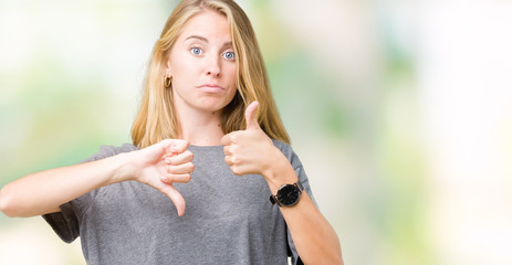 Obraz premium Beautiful young woman wearing oversize casual t-shirt over isolated background Doing thumbs up and down, disagreement and agreement expression. Crazy conflict
