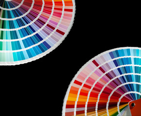 Two color fan decks with samples of various paint in the corners of image, isolated on a black background
