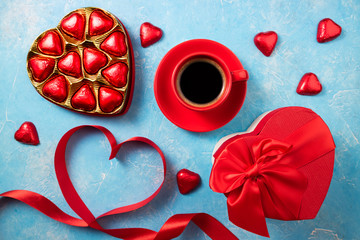 Valentines Day background with red heart, chocolate bonbons and coffee cup. Heart shape from ribbons. Top view