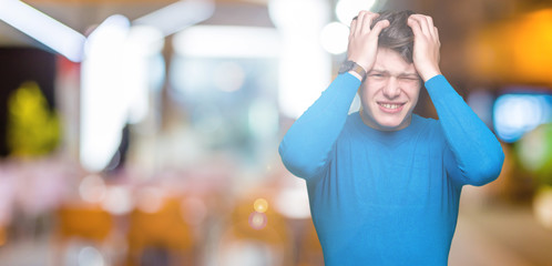 Fototapeta na wymiar Young handsome man wearing blue sweater over isolated background suffering from headache desperate and stressed because pain and migraine. Hands on head.