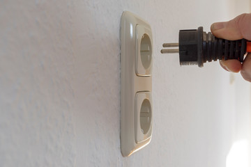 Male hand puts plug in the socket