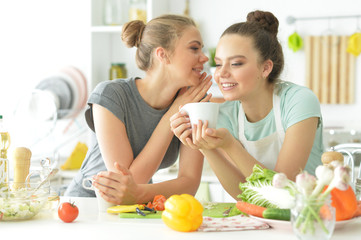 Obraz na płótnie Canvas Portrait of girlfriends in the kitchen drinking tea