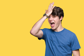 Young handsome man wearing blue t-shirt over isolated background surprised with hand on head for...