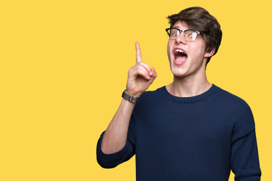 Young handsome man wearing glasses over isolated background pointing finger up with successful idea. Exited and happy. Number one.