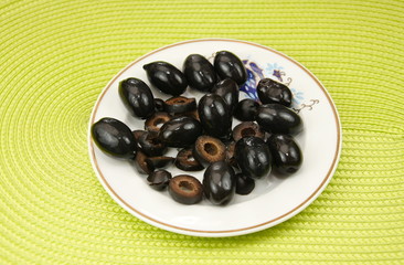 black olives on a  porcelain plate on green  background