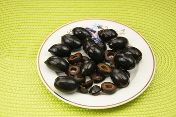 black olives on a  porcelain plate on green  background
