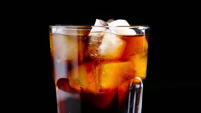 Cola with bubbles poured into a glass of ice.Black background