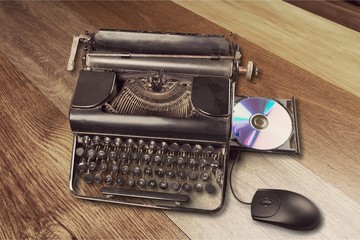 Old typewriter  with computer disk and mouse on background